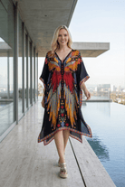 Woman wearing a colorful dress standing by a pool with modern architecture in the background