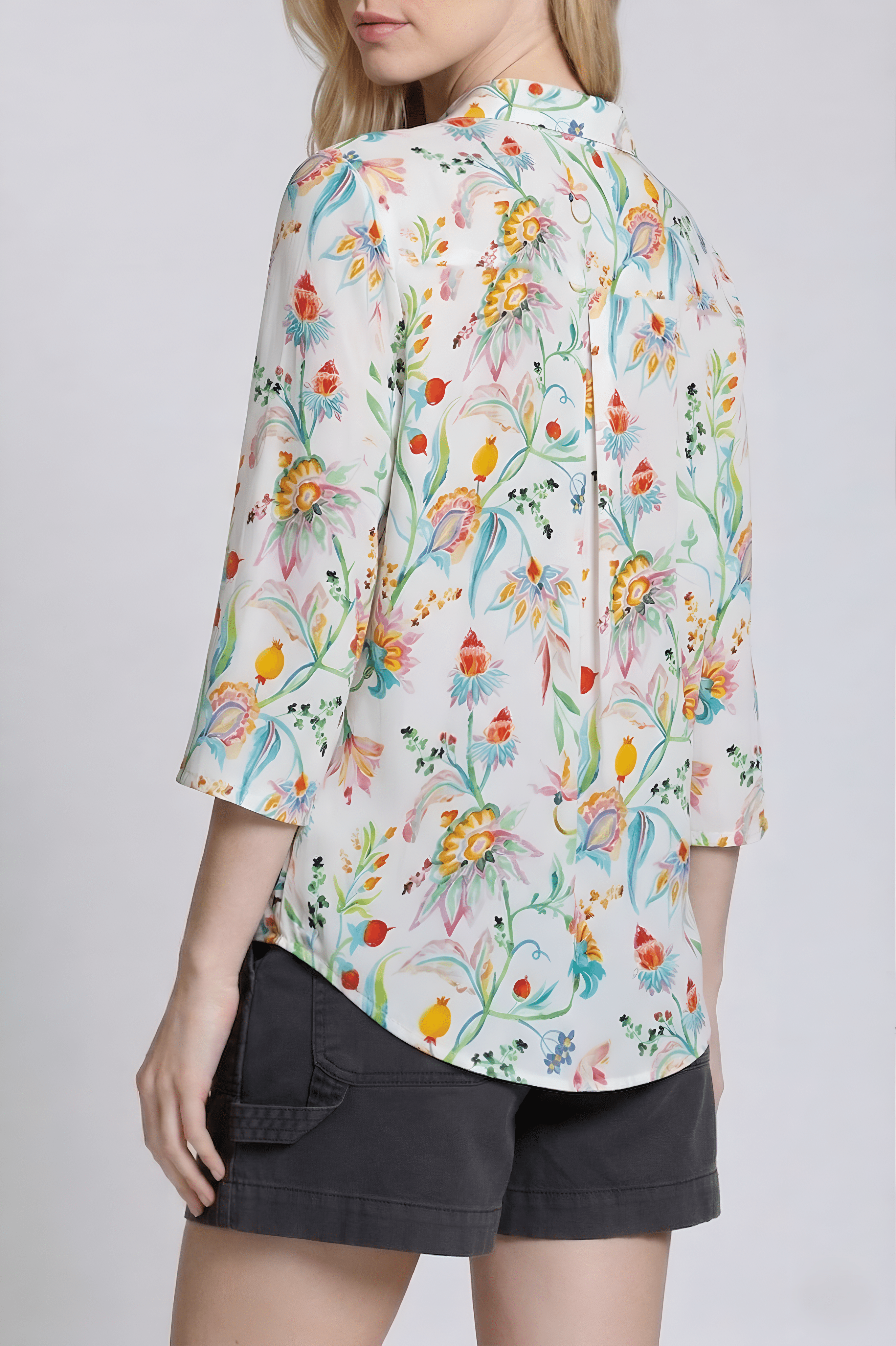 Woman wearing a colorful floral blouse with a plain background