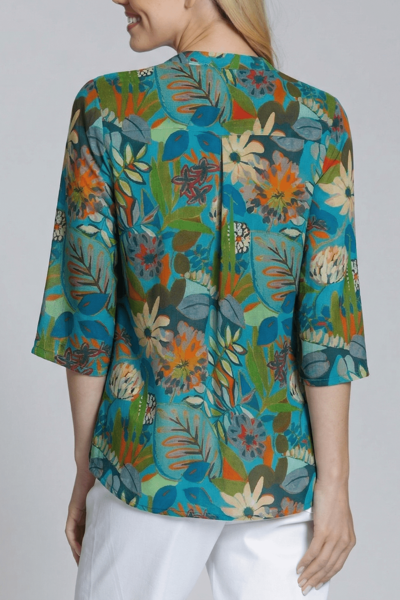 Woman wearing a colorful floral blouse against a plain background