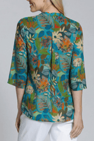 Woman wearing a colorful floral blouse against a plain background