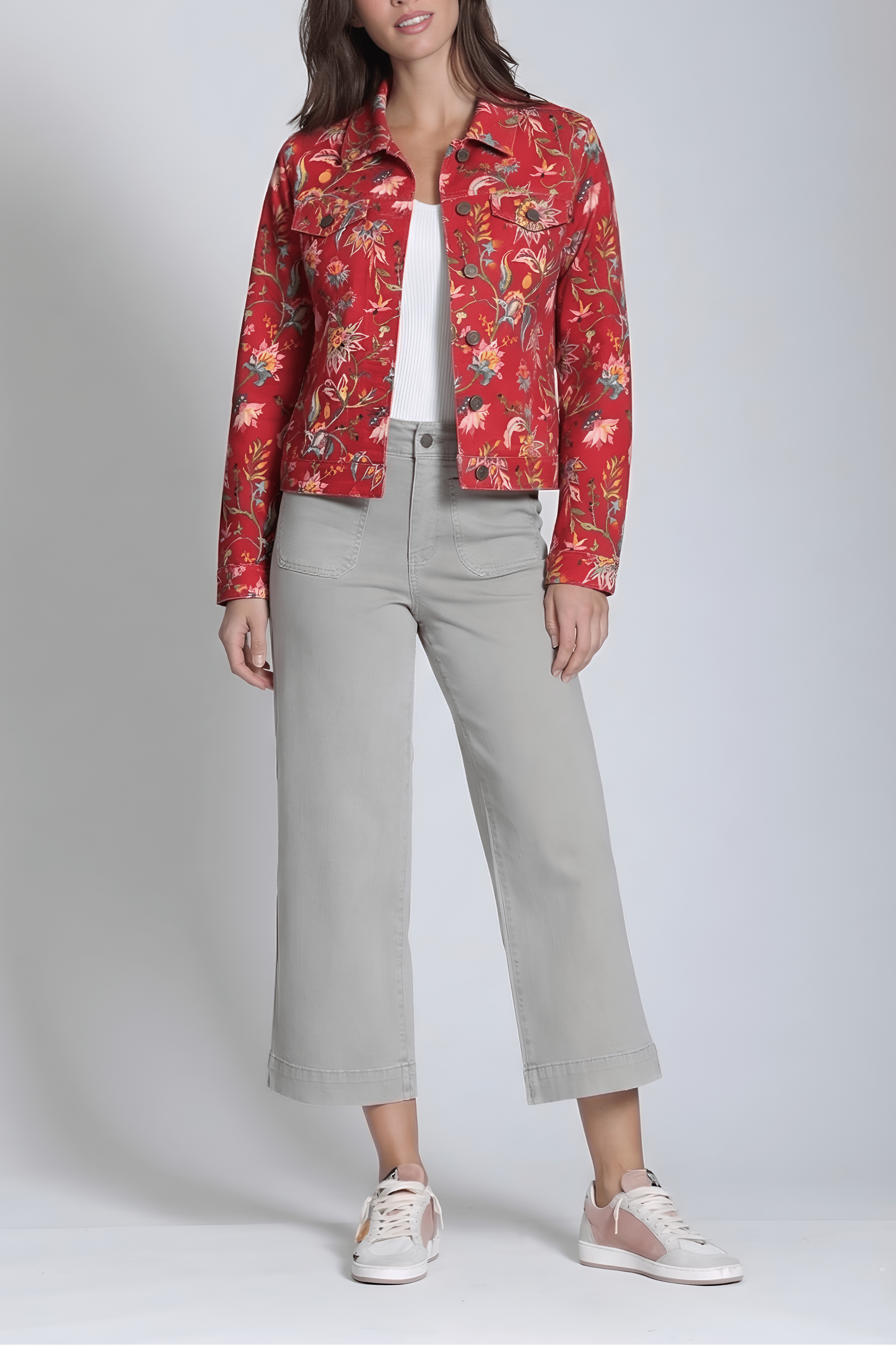 Person wearing a red floral jacket, white shirt, beige pants, and white sneakers on a plain background