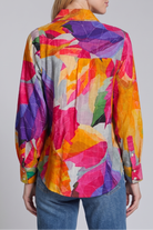 Woman wearing a colorful patterned shirt on a plain background